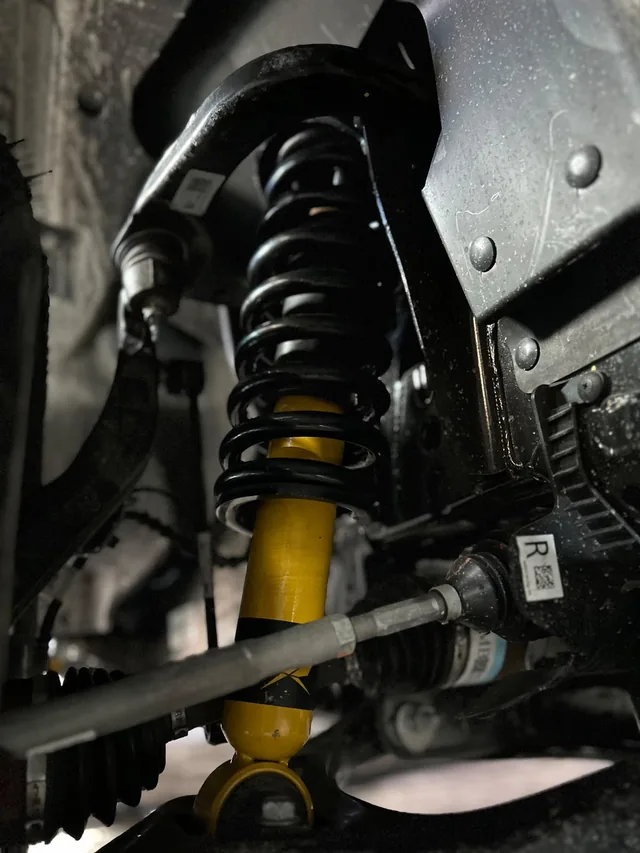 Detalle de la suspensión con resorte negro y amortiguador amarillo