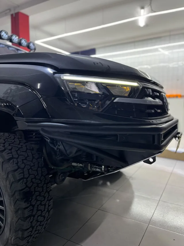 Detalle del frente, faro y neumático de una camioneta negra con equipamiento off road