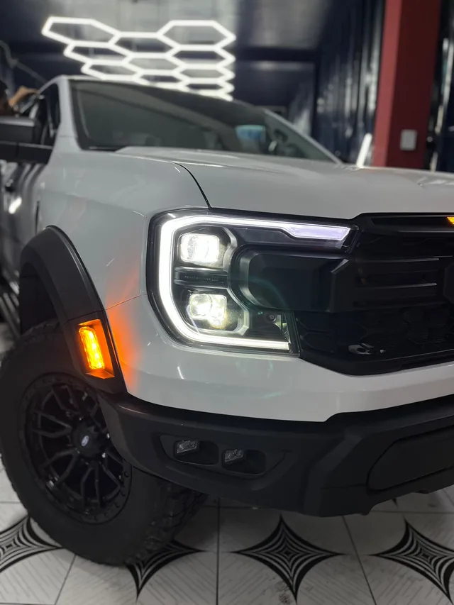 Primer plano de los faros encendidos de una camioneta Ford blanca