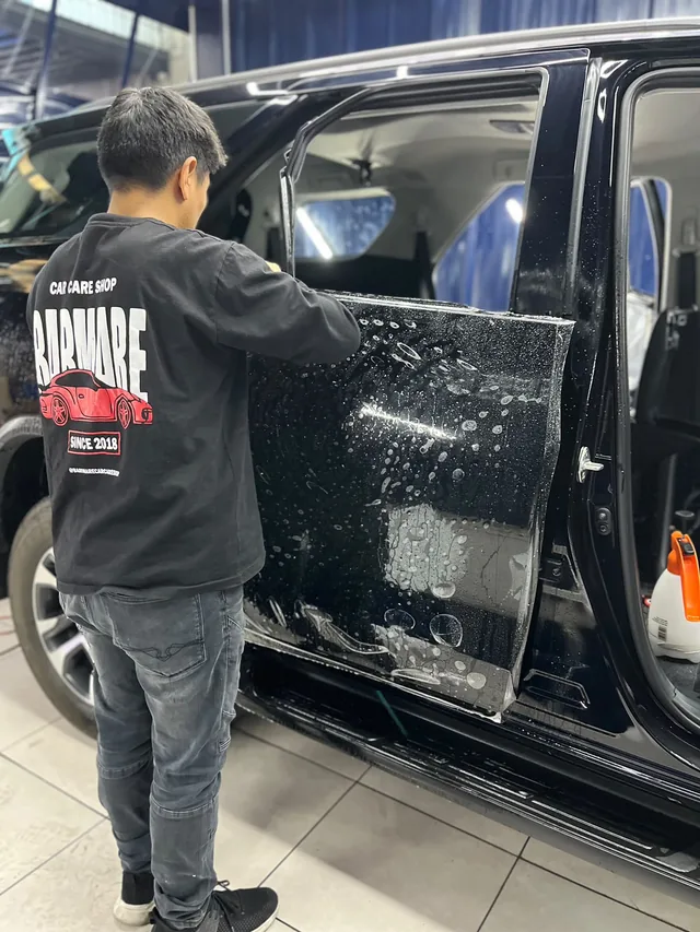Integrante del equipo BARMARE aplicando película sobre la puerta de una camioneta negra